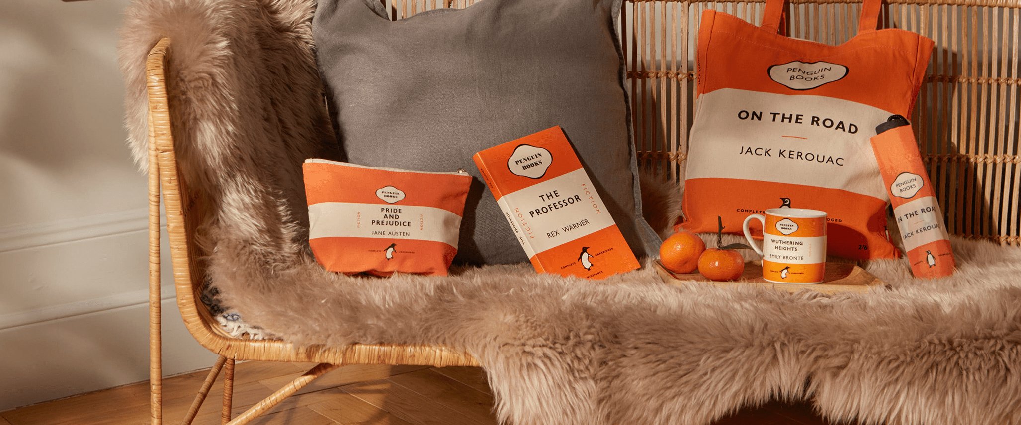Penguin Collection notebook, pencil case, tote, mug and umbrella displayed on a blanketed chair