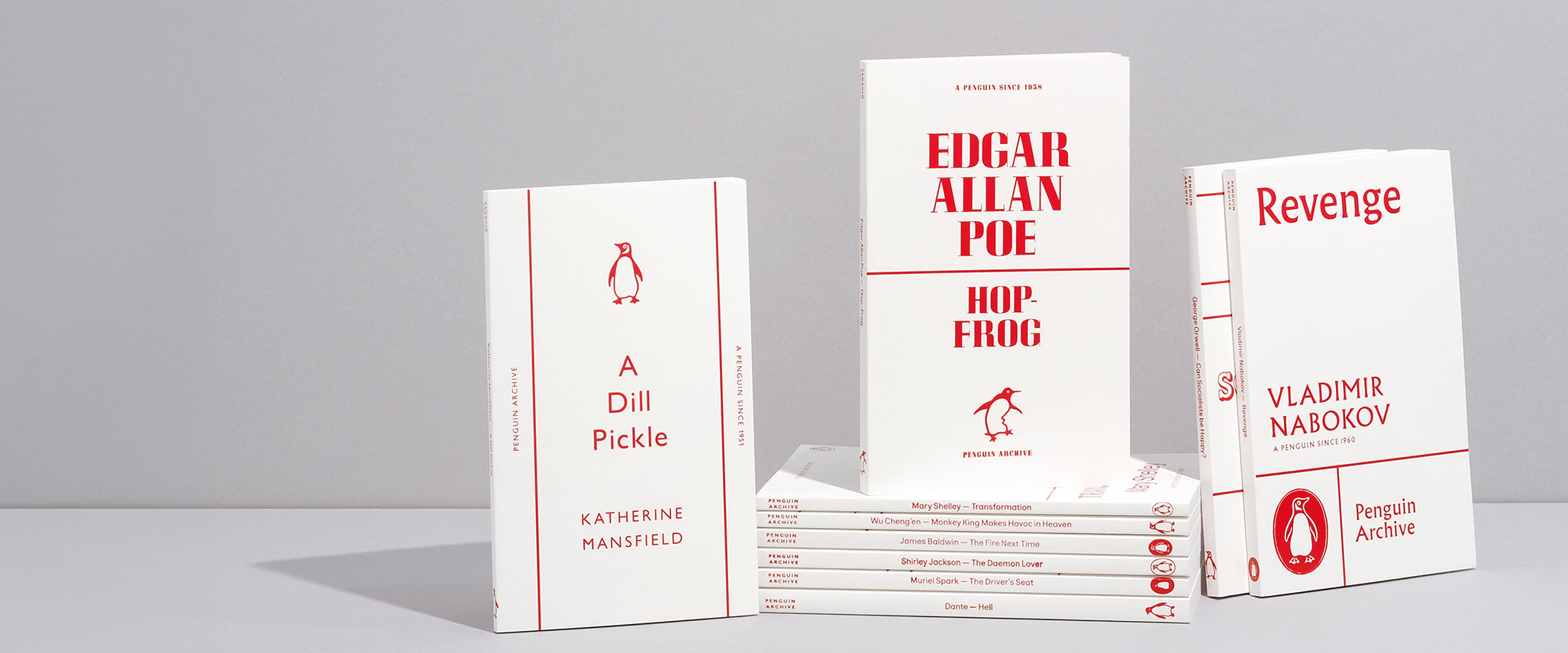 A collection of small white paperbacks with red text and images on the covers from the Penguin Archive Collection